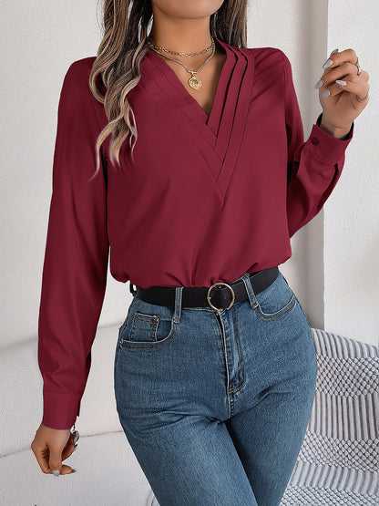 Burgundy - Women's long-sleeve blouse featuring a distinctive pleated V-neckline and buttoned cuffs, styled tucked into blue denim jeans.