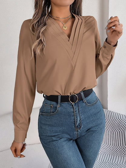 Pink - Women's long-sleeve blouse featuring a distinctive pleated V-neckline and buttoned cuffs, styled tucked into blue denim jeans.
