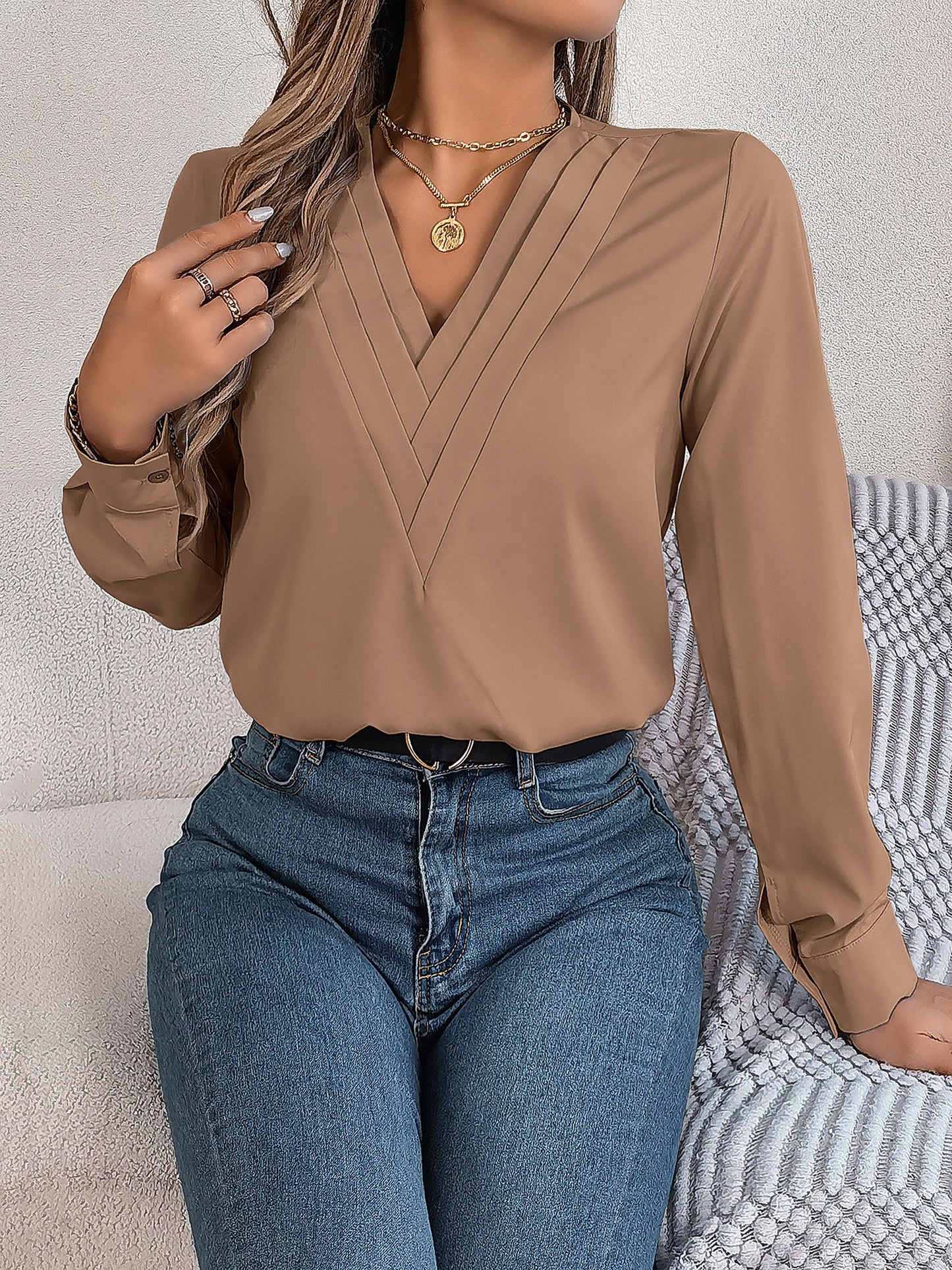 Pink - Women's long-sleeve blouse featuring a distinctive pleated V-neckline and buttoned cuffs, styled tucked into blue denim jeans.