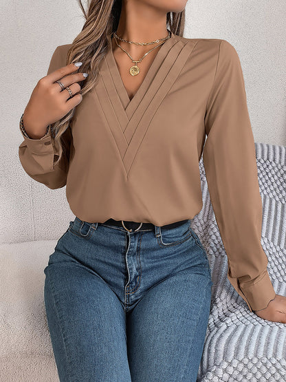 Pink - Women's long-sleeve blouse featuring a distinctive pleated V-neckline and buttoned cuffs, styled tucked into blue denim jeans.