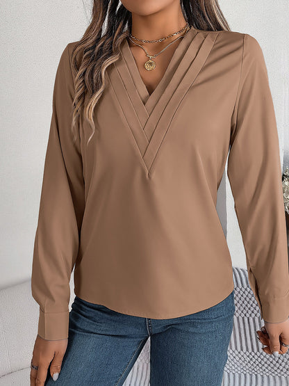 Pink - Women's long-sleeve blouse featuring a distinctive pleated V-neckline and buttoned cuffs, styled tucked into blue denim jeans.