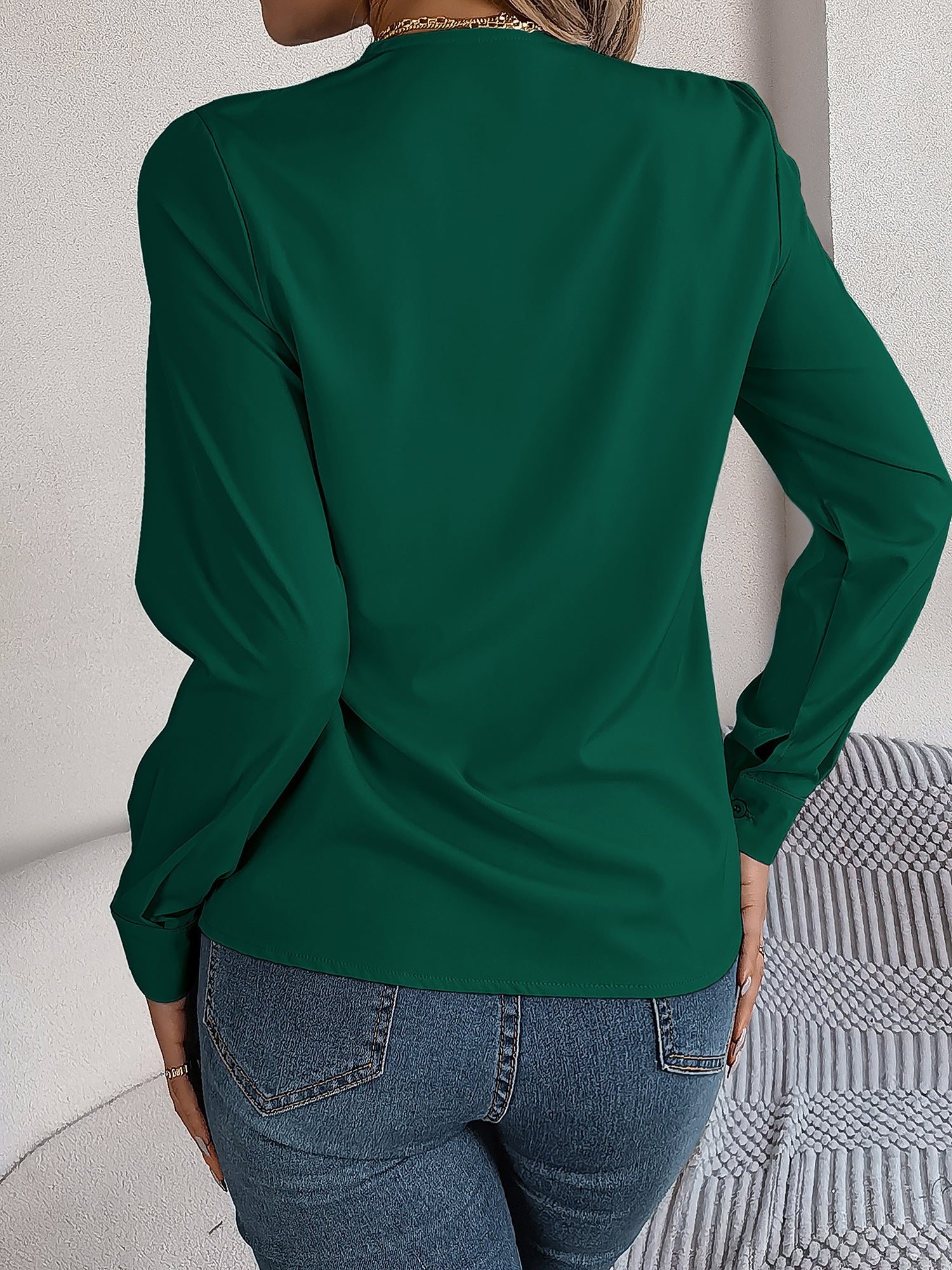Burgundy - Women's long-sleeve blouse featuring a distinctive pleated V-neckline and buttoned cuffs, styled tucked into blue denim jeans.