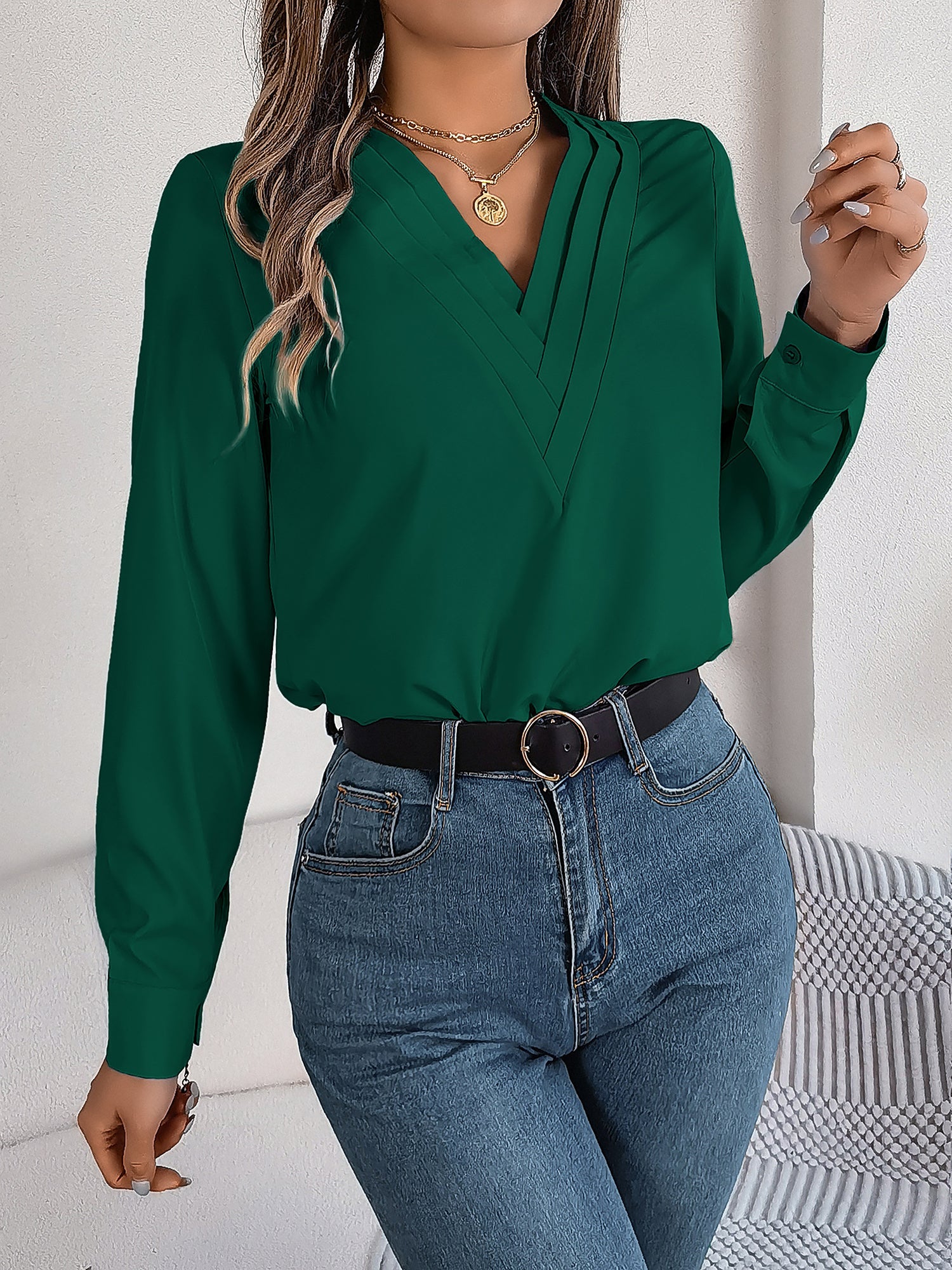 Burgundy - Women's long-sleeve blouse featuring a distinctive pleated V-neckline and buttoned cuffs, styled tucked into blue denim jeans.