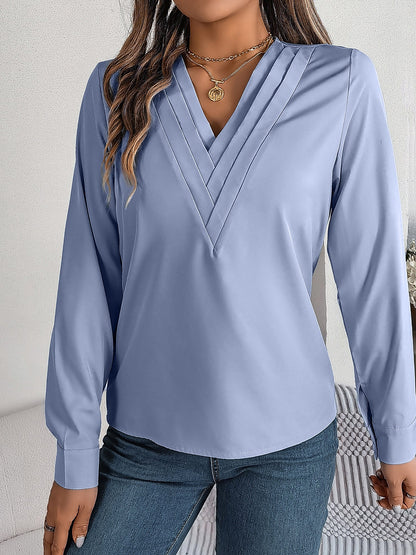 Blue - Women's long-sleeve blouse featuring a distinctive pleated V-neckline and buttoned cuffs, styled tucked into blue denim jeans.