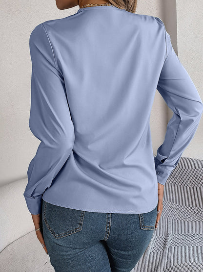 Blue - Women's long-sleeve blouse featuring a distinctive pleated V-neckline and buttoned cuffs, styled tucked into blue denim jeans.