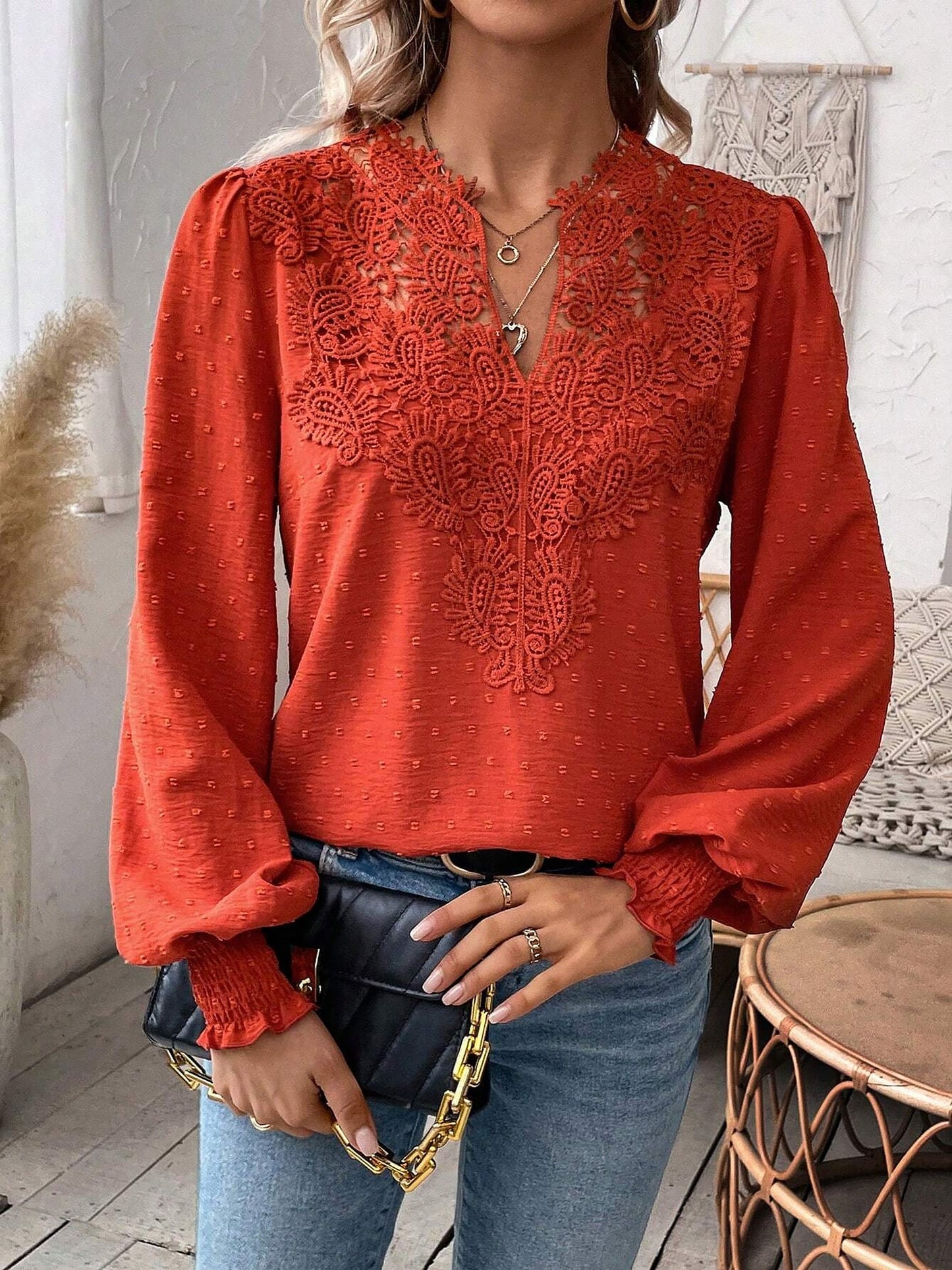 Red - Women's dusty rose long-sleeve blouse featuring a lace V-neckline, textured Swiss dot fabric, and smocked cuffs, styled with blue jeans.