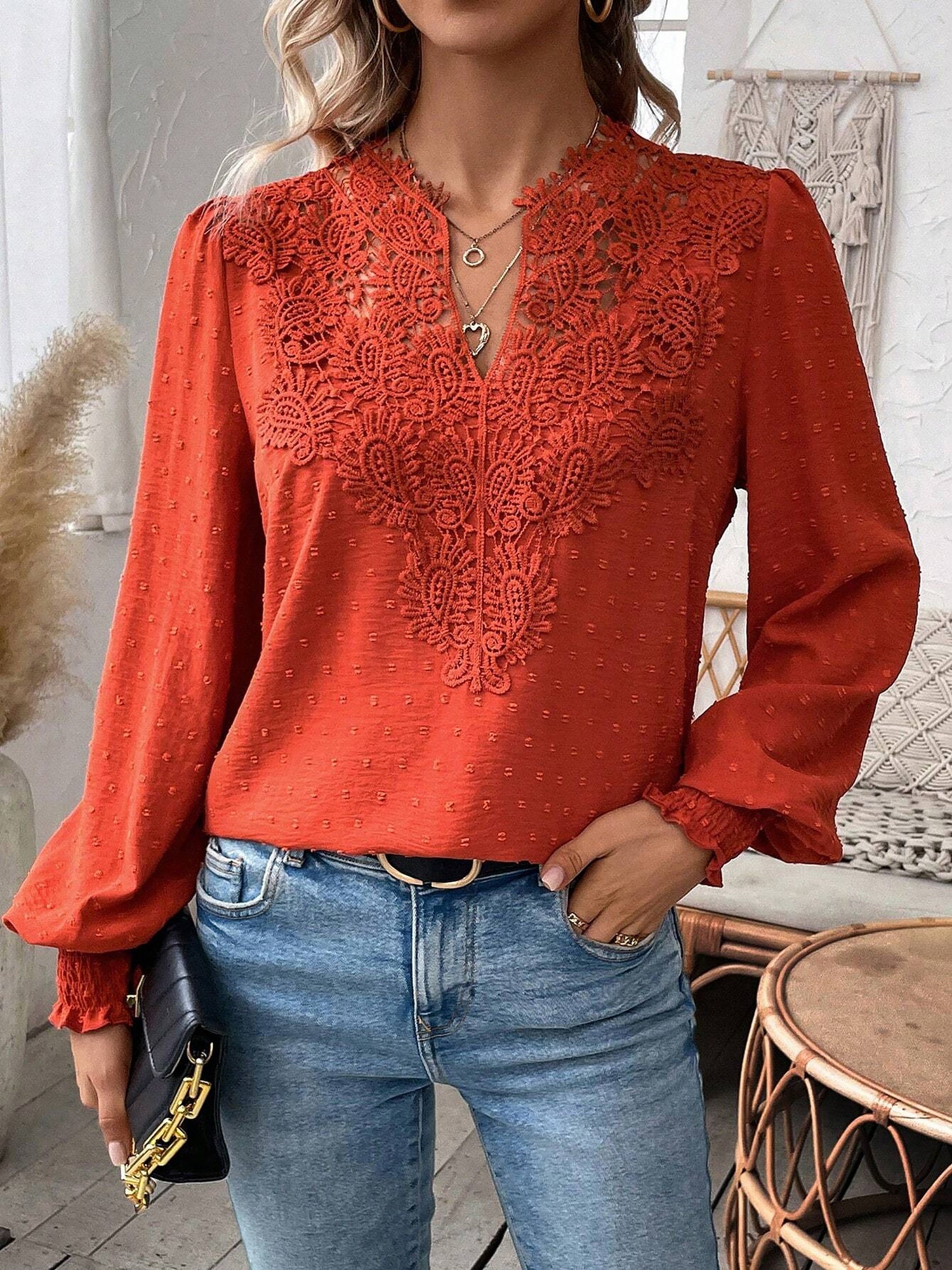 Red - Women's dusty rose long-sleeve blouse featuring a lace V-neckline, textured Swiss dot fabric, and smocked cuffs, styled with blue jeans.