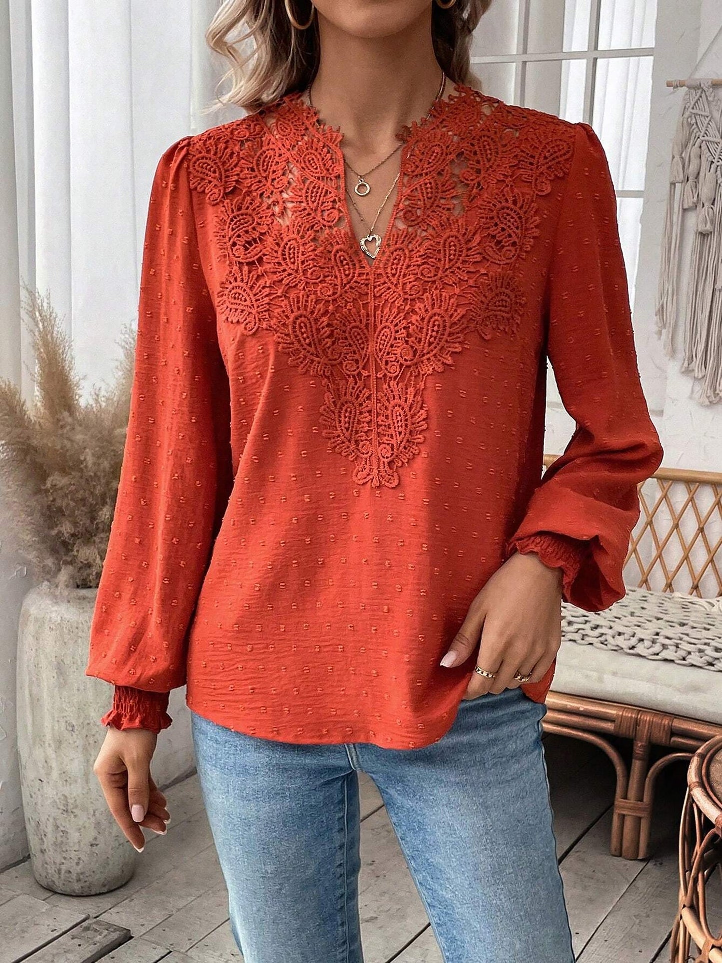 Red - Women's dusty rose long-sleeve blouse featuring a lace V-neckline, textured Swiss dot fabric, and smocked cuffs, styled with blue jeans.