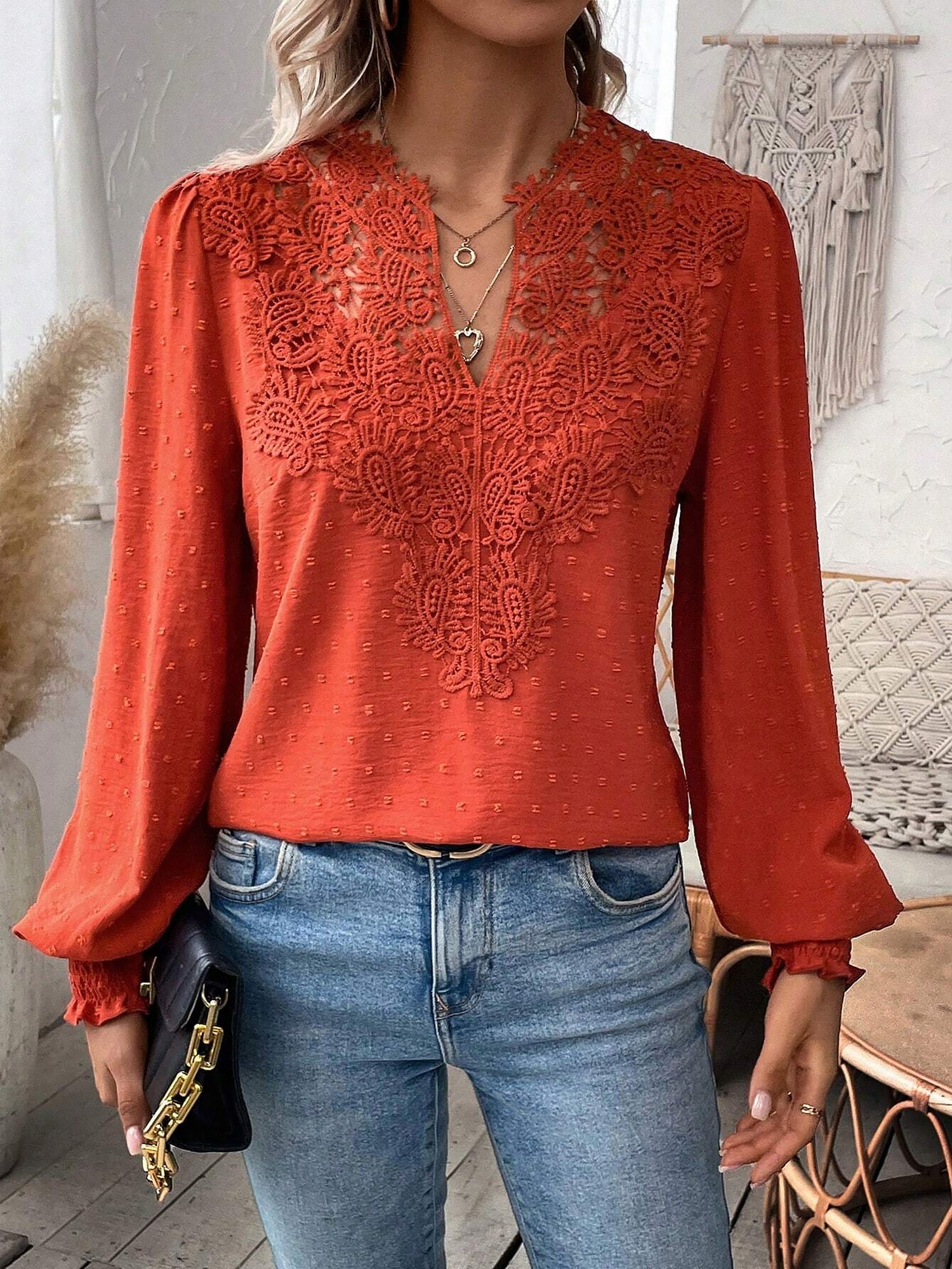 Red - Women's dusty rose long-sleeve blouse featuring a lace V-neckline, textured Swiss dot fabric, and smocked cuffs, styled with blue jeans.