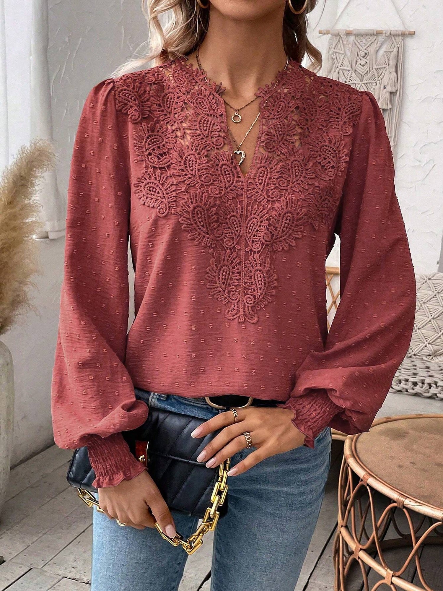 Watermelon Red - Women's dusty rose long-sleeve blouse featuring a lace V-neckline, textured Swiss dot fabric, and smocked cuffs, styled with blue jeans.