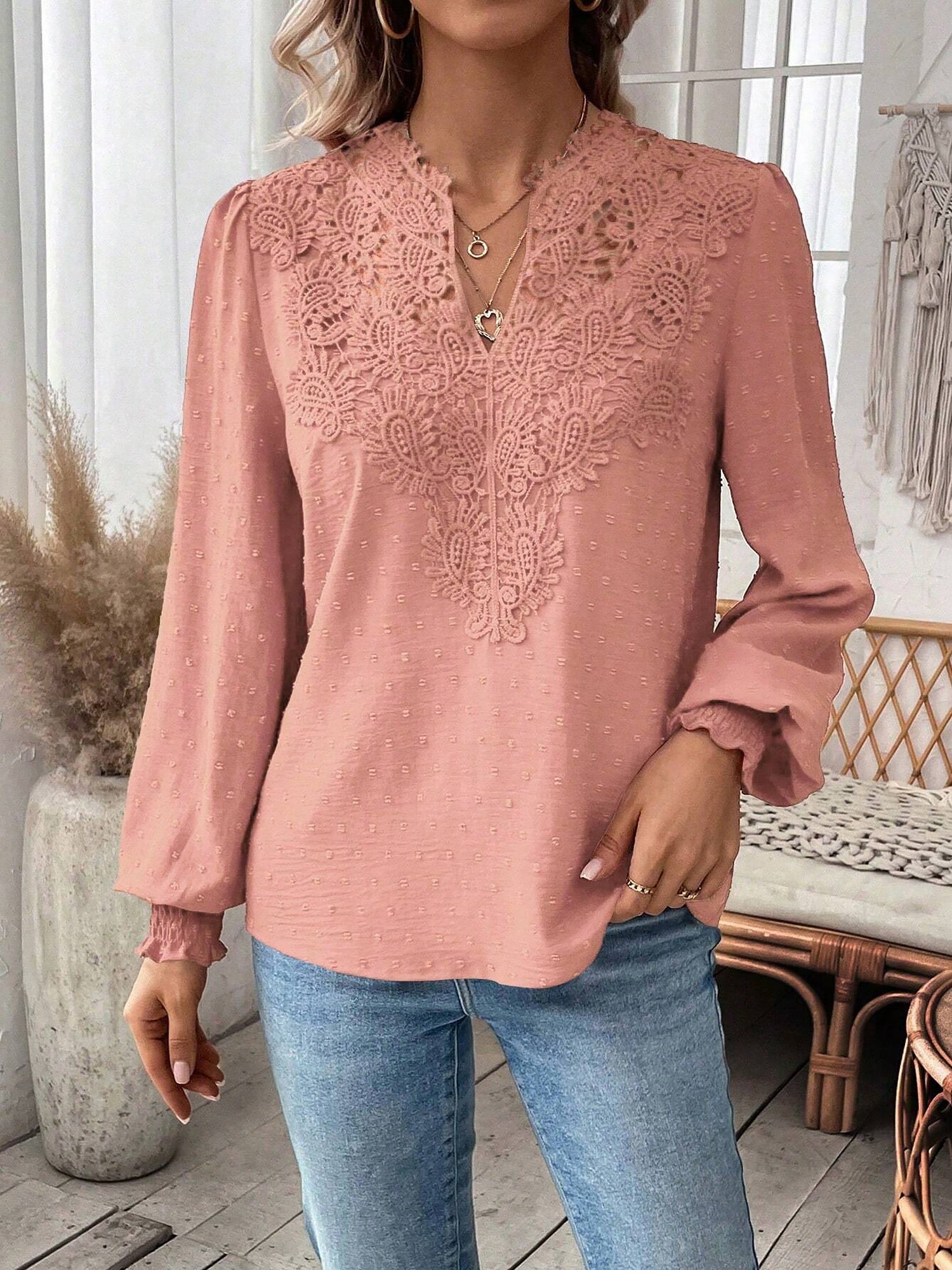 Pink - Women's dusty rose long-sleeve blouse featuring a lace V-neckline, textured Swiss dot fabric, and smocked cuffs, styled with blue jeans.