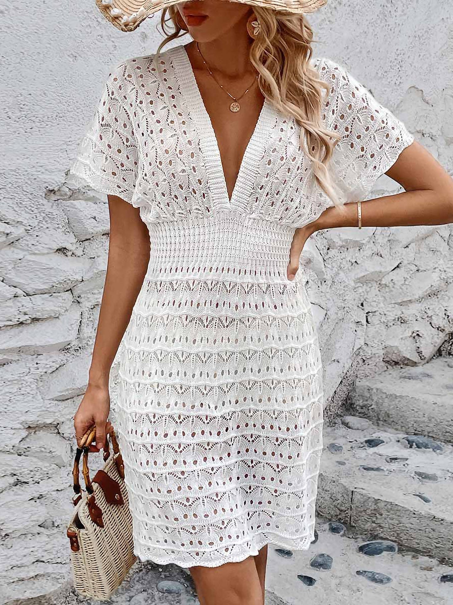 White - A woman wears a white, short-sleeve mini cover-up featuring a deep V-neck, a wide smocked waist, and an all-over geometric open-knit pattern.