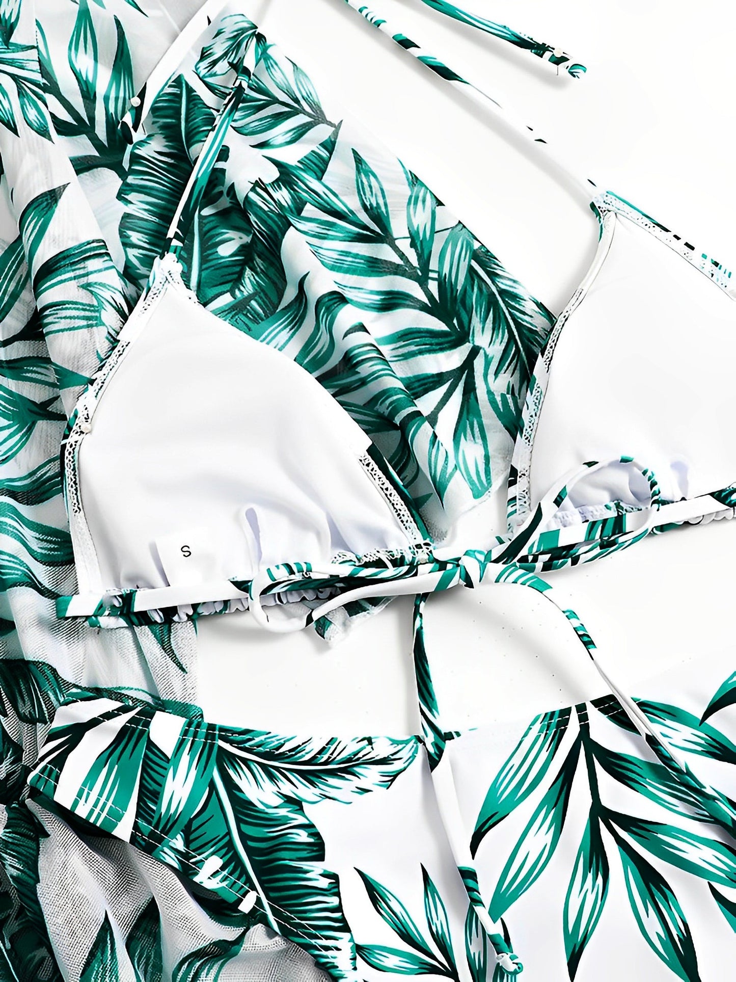 Green - A woman models a sheer, short-sleeve mini cover-up with a vibrant tropical leaf print in shades of purple, blue, and pink, featuring a deep V-neck, drawstring waist, and ruched sides with ties.