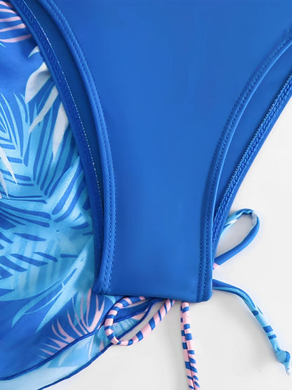 Royal Blue - A woman models a sheer, short-sleeve mini cover-up with a vibrant tropical leaf print in shades of purple, blue, and pink, featuring a deep V-neck, drawstring waist, and ruched sides with ties.