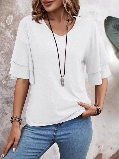 White - Women's solid pink V-neck blouse featuring tiered ruffle short sleeves, styled with blue jeans and a long pendant necklace.
