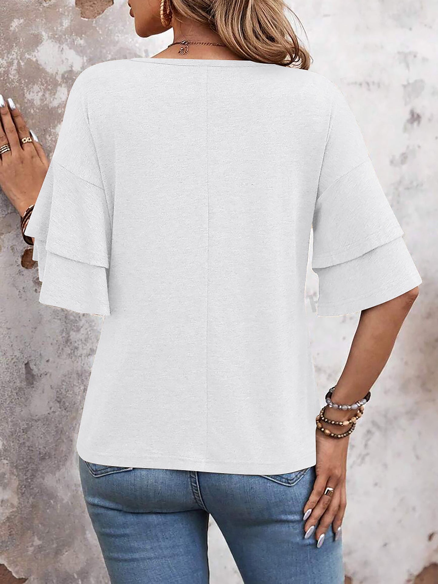 White - Women's solid pink V-neck blouse featuring tiered ruffle short sleeves, styled with blue jeans and a long pendant necklace.