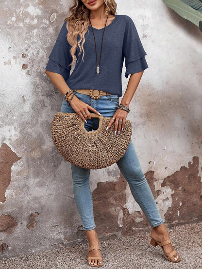 Navy Blue - Women's solid pink V-neck blouse featuring tiered ruffle short sleeves, styled with blue jeans and a long pendant necklace.