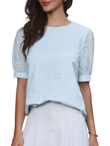 Light Blue - A woman models a light blue, short-sleeve eyelet blouse with a round neckline, paired with white wide-leg trousers.
