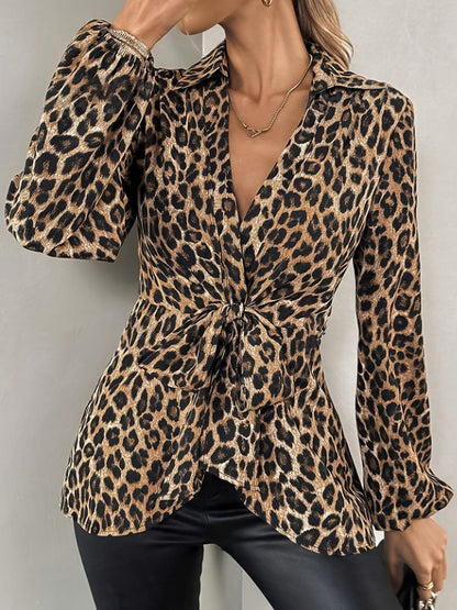 Brown - A woman wearing a long-sleeved, collared, tie-front blouse in a brown and black leopard print, paired with black pants.