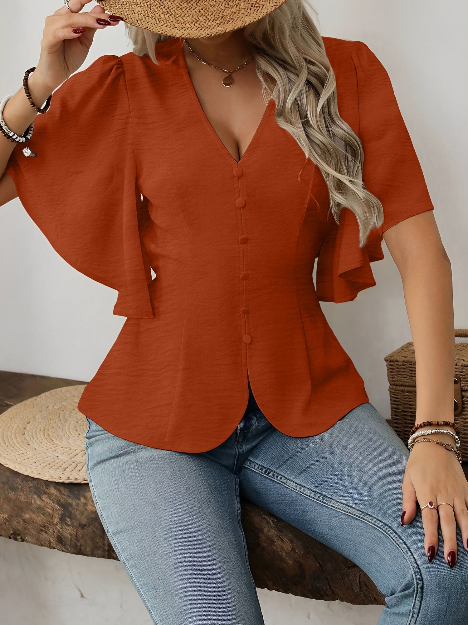 Brown - Women's rust orange short flutter sleeve blouse featuring a V-neckline, fabric-covered button front, and a tailored peplum waist, styled with blue jeans.
