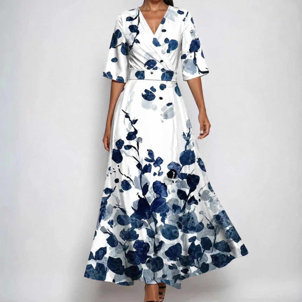 White - A woman wearing a cream-colored maxi dress featuring a watercolor floral print in blue, purple, and yellow, designed with a surplice V-neck, wide elbow-length sleeves, and a flowing skirt.