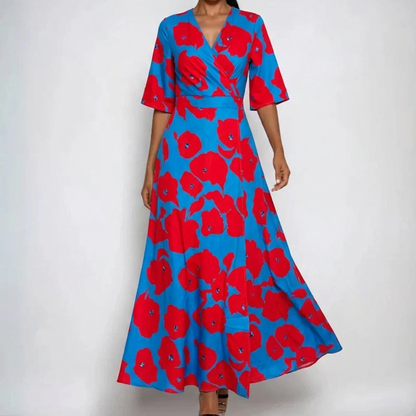 Red - A woman wearing a cream-colored maxi dress featuring a watercolor floral print in blue, purple, and yellow, designed with a surplice V-neck, wide elbow-length sleeves, and a flowing skirt.