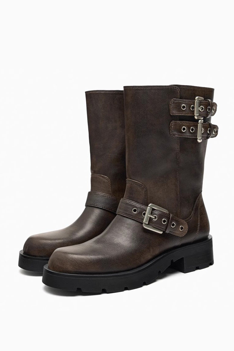 A pair of women's dark brown faux leather mid-calf moto boots featuring three adjustable buckle straps and a chunky black lug sole.