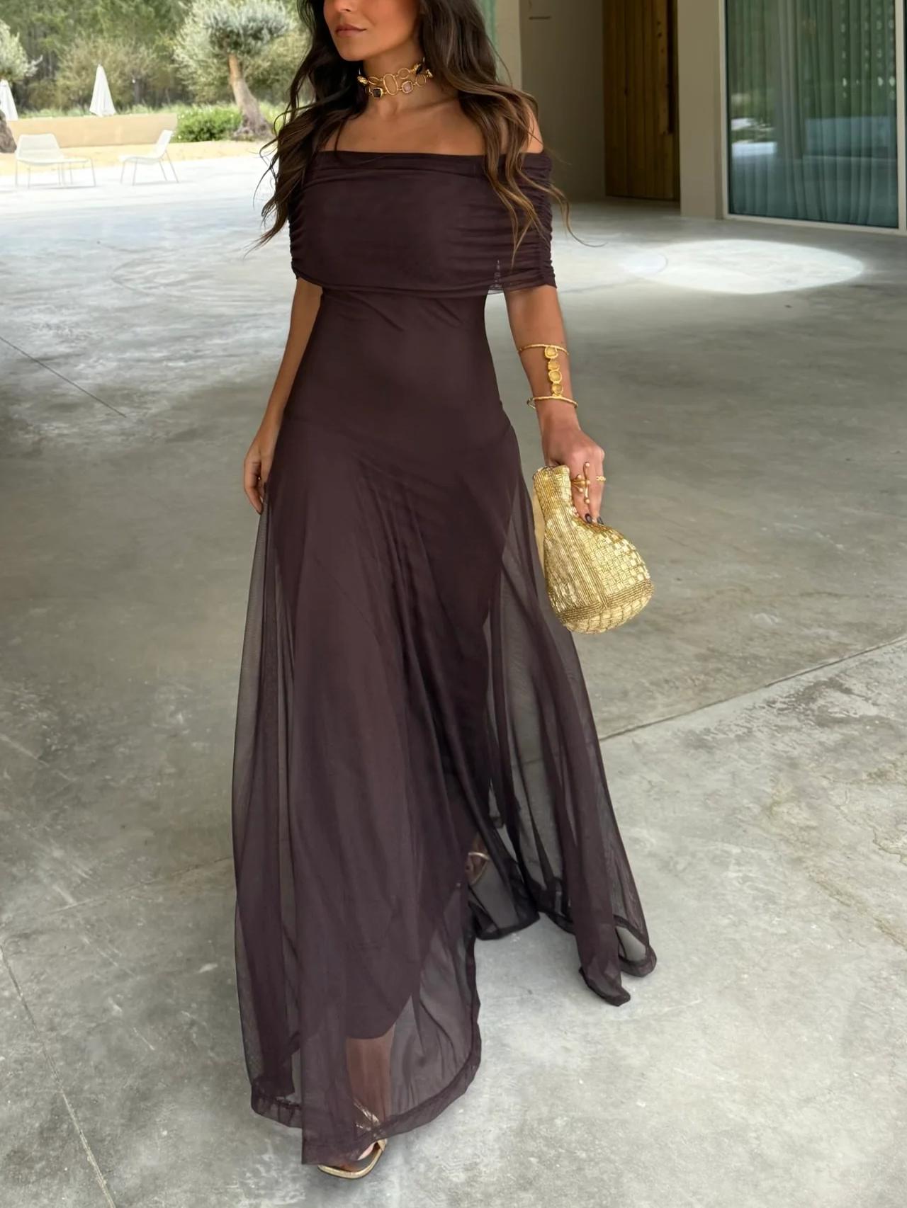 Brown - A woman wearing a dark brown, formal off-the-shoulder maxi dress featuring a ruched neckline and a flowing sheer mesh overlay over a fitted underlay, styled with gold accessories.
