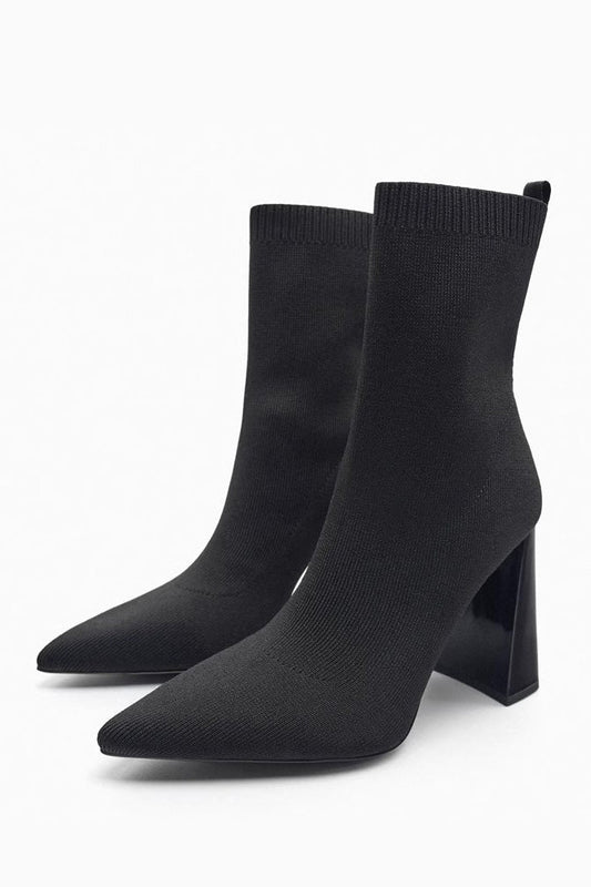 Women's black ribbed knit ankle sock boots featuring a pointed toe and a shiny block heel.