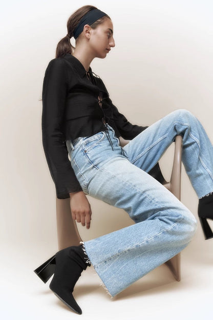 Women's black ribbed knit ankle sock boots featuring a pointed toe and a shiny block heel.
