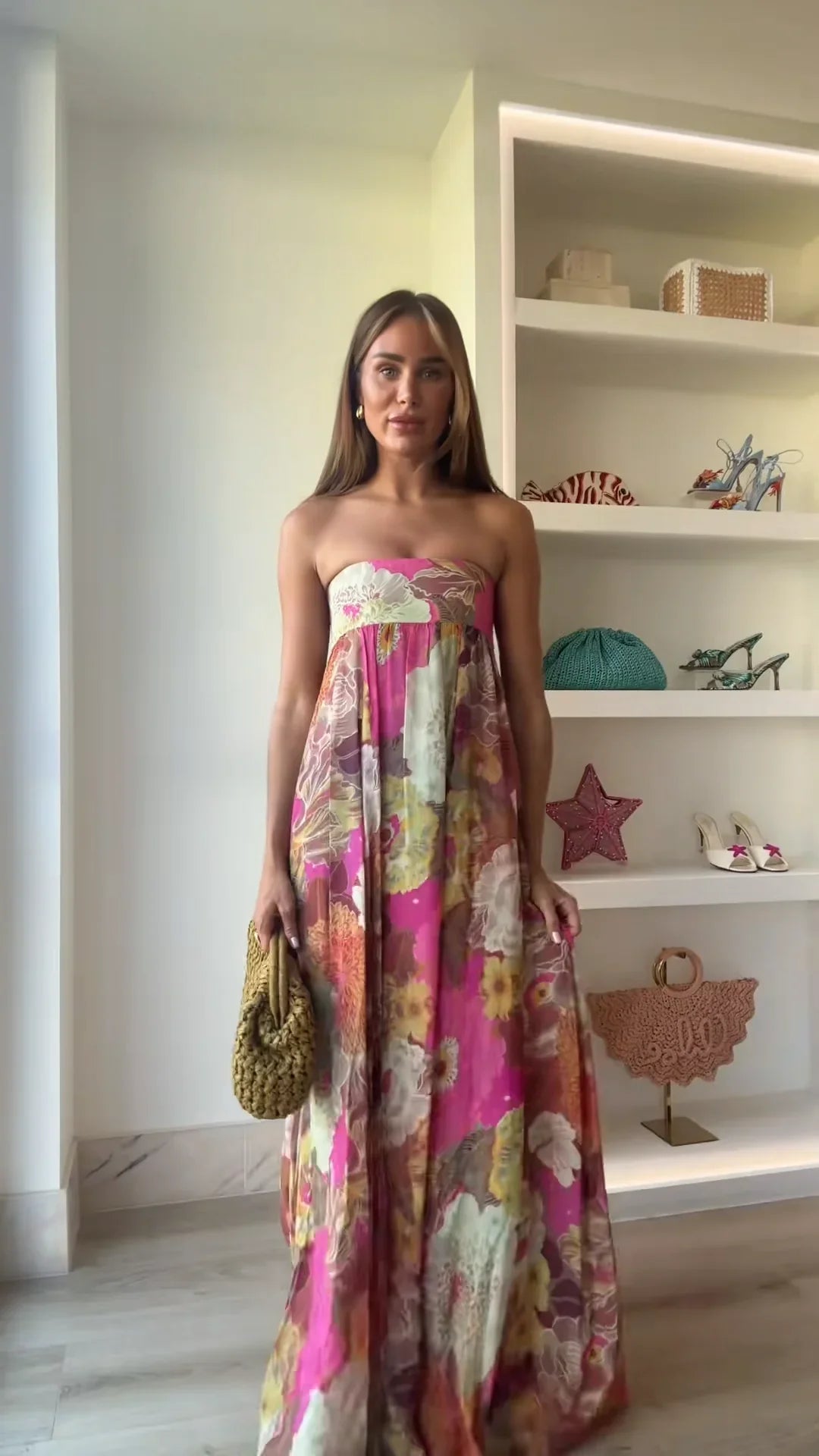 Multicolor - A woman wearing a strapless, flowing maxi dress featuring a vibrant, large-scale floral print in shades of pink, yellow, and green.