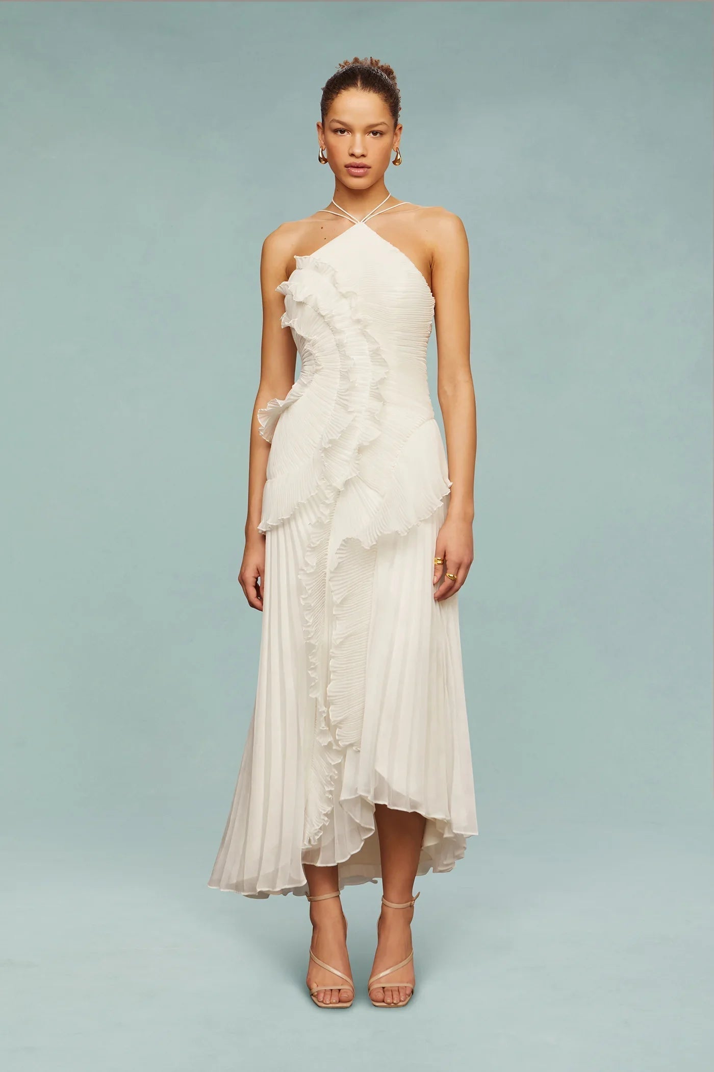 White - A woman wearing an elegant light purple midi dress featuring a halter neckline, all-over micro-pleating, and a dramatic asymmetrical cascading ruffle detail down the front.