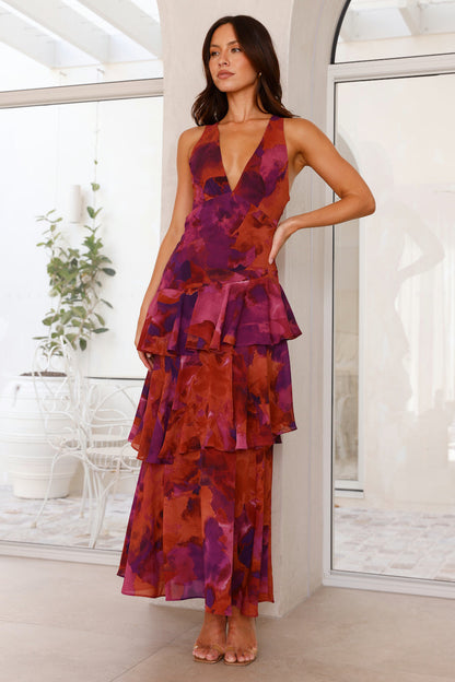 Yellow - A woman wearing a vibrant teal and blue abstract floral print maxi dress featuring a deep V-neckline and a dramatic tiered ruffle skirt.