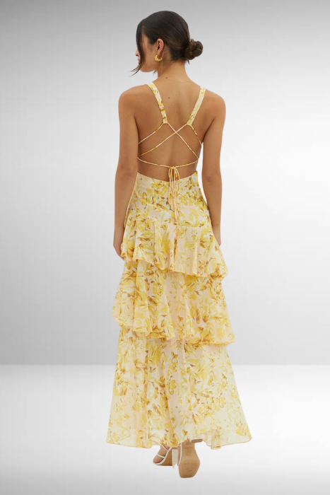 Yellow - A woman wearing a vibrant teal and blue abstract floral print maxi dress featuring a deep V-neckline and a dramatic tiered ruffle skirt.