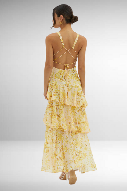 Yellow - A woman wearing a vibrant teal and blue abstract floral print maxi dress featuring a deep V-neckline and a dramatic tiered ruffle skirt.