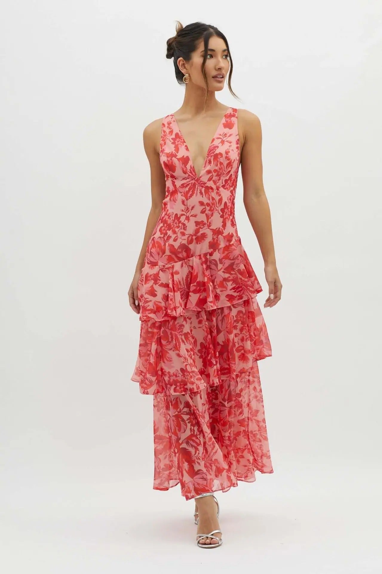 Red - A woman wearing a vibrant teal and blue abstract floral print maxi dress featuring a deep V-neckline and a dramatic tiered ruffle skirt.