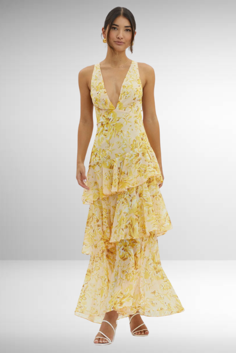 Yellow - A woman wearing a vibrant teal and blue abstract floral print maxi dress featuring a deep V-neckline and a dramatic tiered ruffle skirt.