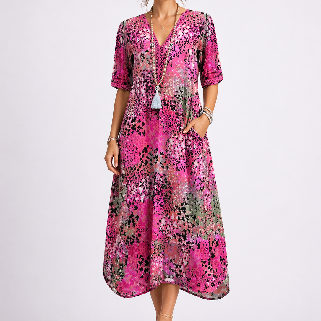 Pink - Woman wearing a relaxed fit abstract print midi dress with short sleeves, a V-neckline, and side pockets against a plain background.