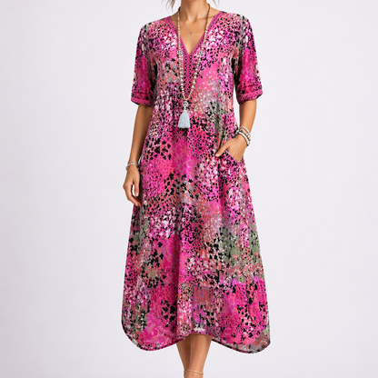 Pink - Woman wearing a relaxed fit abstract print midi dress with short sleeves, a V-neckline, and side pockets against a plain background.