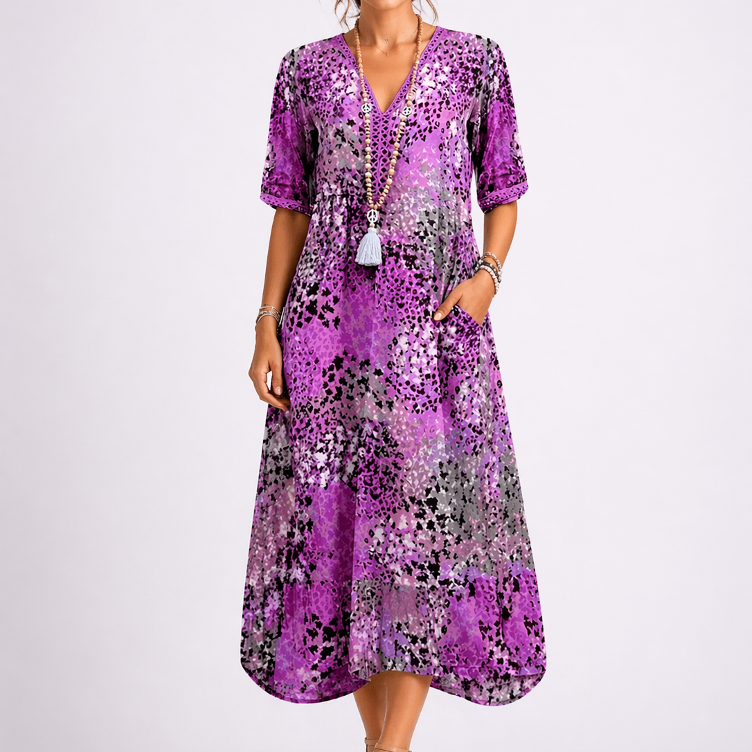 Purple - Woman wearing a relaxed fit abstract print midi dress with short sleeves, a V-neckline, and side pockets against a plain background.