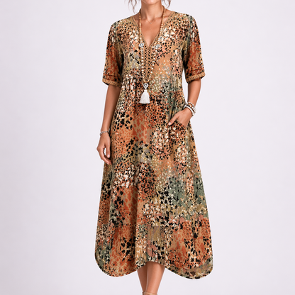 Sand & Beige - Woman wearing a relaxed fit abstract print midi dress with short sleeves, a V-neckline, and side pockets against a plain background.