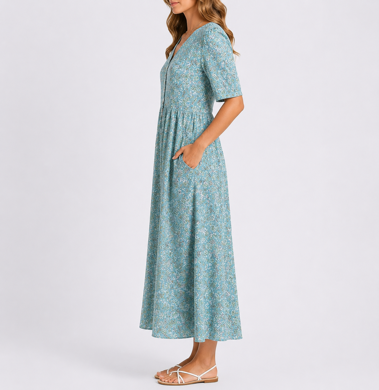 A woman wearing a woven floral smock midi dress with short sleeves and a gathered waist, standing with her hands in the side pockets against a plain light background.