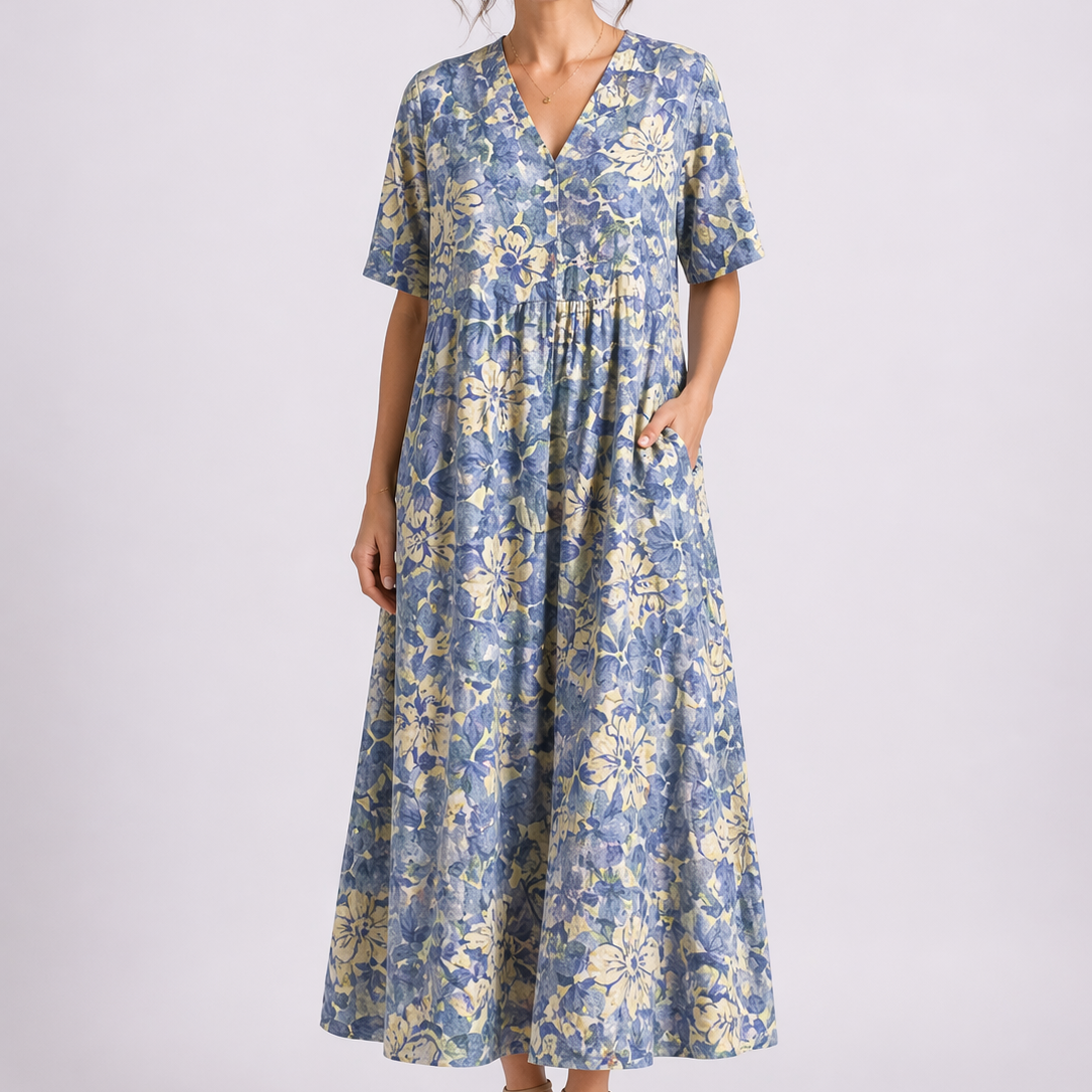 Blue - Model wearing a woven floral V-neck midaxi dress with short sleeves and side pockets against a plain grey background.