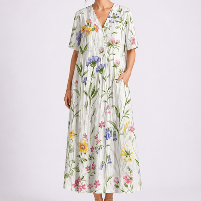 White - Model wearing a woven floral V-neck midaxi dress with short sleeves and side pockets against a plain grey background.