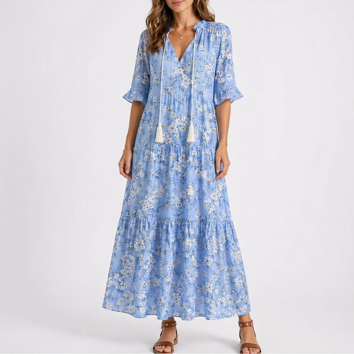 Blue & White - Woman wearing a woven ikat pattern maxi dress with a V-neck, tassel ties, 3/4-sleeves, and a tiered hemline against a light grey background.
