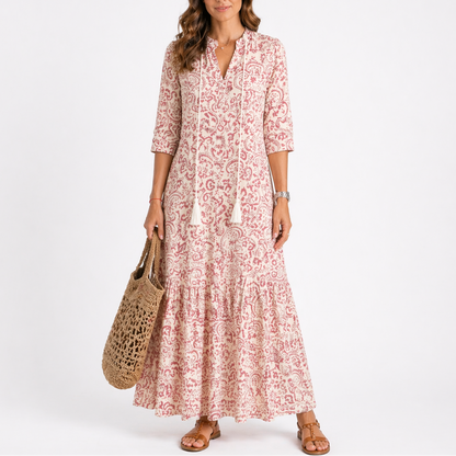 Red - Woman wearing a woven ikat pattern maxi dress with a V-neck, tassel ties, 3/4-sleeves, and a tiered hemline against a light grey background.