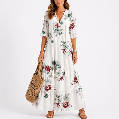 Floral - Woman wearing a woven ikat pattern maxi dress with a V-neck, tassel ties, 3/4-sleeves, and a tiered hemline against a light grey background.
