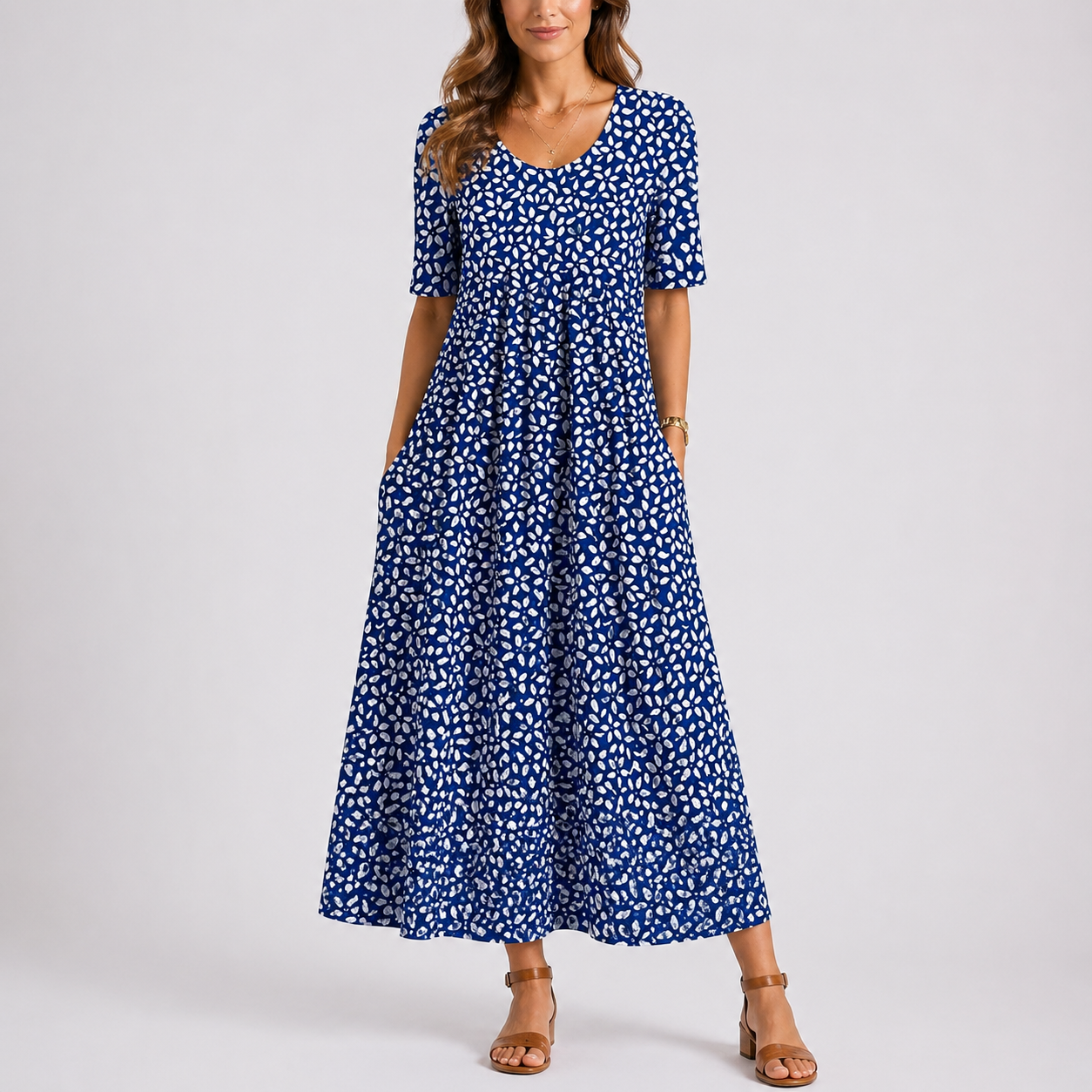 Blue - Model wearing a printed short-sleeve midaxi dress with a scoop neckline, gathered waist, and side pockets, standing against a plain light grey background.