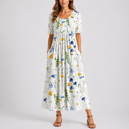 Floral White - Model wearing a printed short-sleeve midaxi dress with a scoop neckline, gathered waist, and side pockets, standing against a plain light grey background.